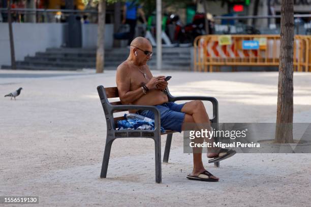 Shirtless man rests on a bench in the shade on a very hot afternoon on July 19, 2023 in Madrid, Spain. An area of high pressure, named Cerberus after...