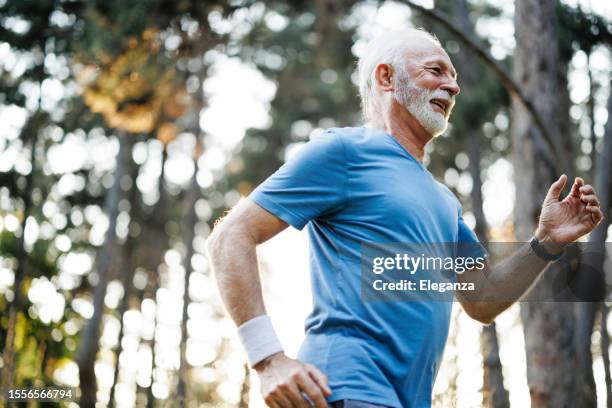 sporty senior man jogging in nature park - homens de idade mediana imagens e fotografias de stock