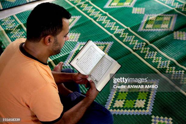 Lebanese Sunni Muslim worshipper reads the Koran before the start of the Friday noon prayer on August 27, 2010 at a damaged mosque in the mainly...