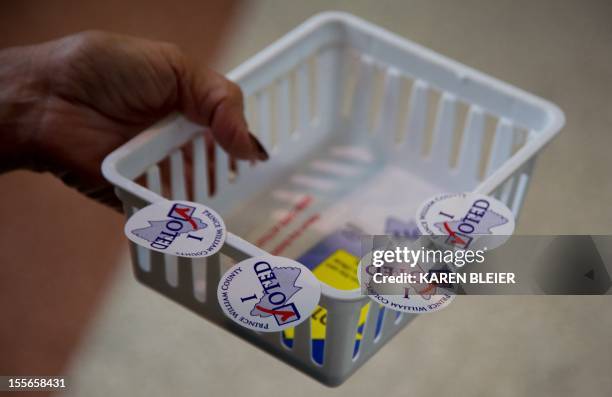 Voting official hands out "I Voted" stickers at Battlefield High School November 6, 2012 in Gainesville, Prince William County, Virginia. After a...