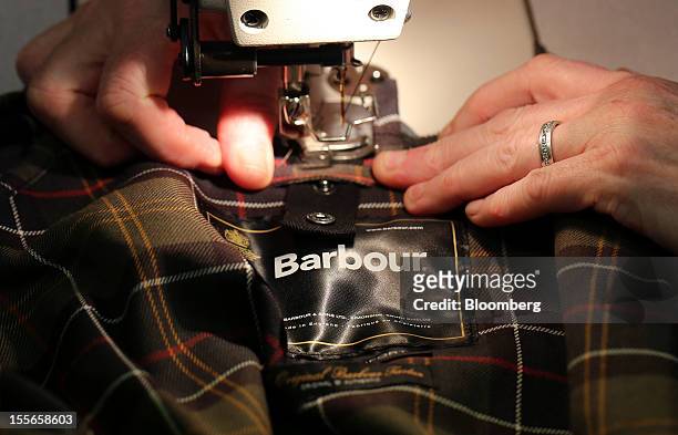 An employee uses a sewing machine to stitch material to the collar of a Barbour jacket during production at the headquarters of J. Barbour & Sons...