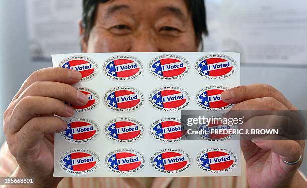 Election official Henry Tung displays a sheet of "I Voted" stickers in various languages at a polling station at St. Paul's Lutheran Church in...