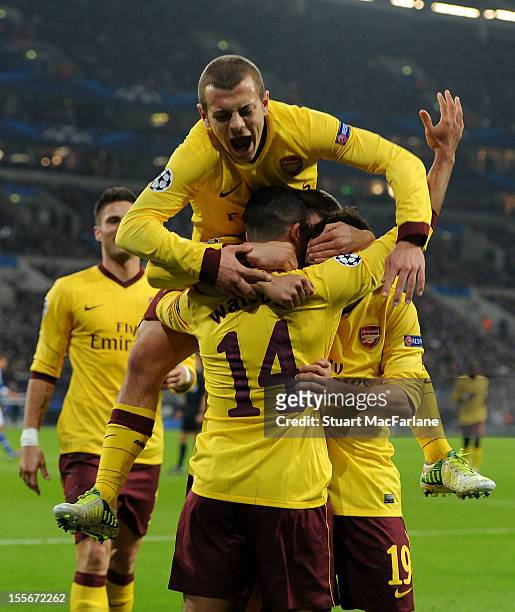 Theo Walcott of Arsenal celebrates with team-mates Jack Wilshere and Santi Cazorla after scoring his team's first goal during the UEFA Champions...