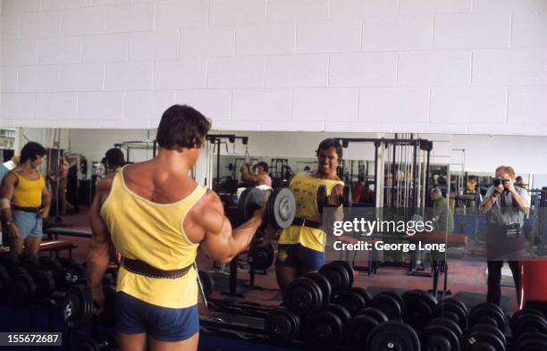 View of bodybuilder Arnold Schwarzenegger lifting weight during training session photo shoot at Gold's Gym. Los Angeles, CA 8/22/1974 CREDIT: George...