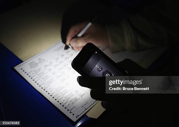 Displaced from his assigned polling location, Larry Zassman of Oceanside marks his ballot via cell phone light at the generator powered First United...