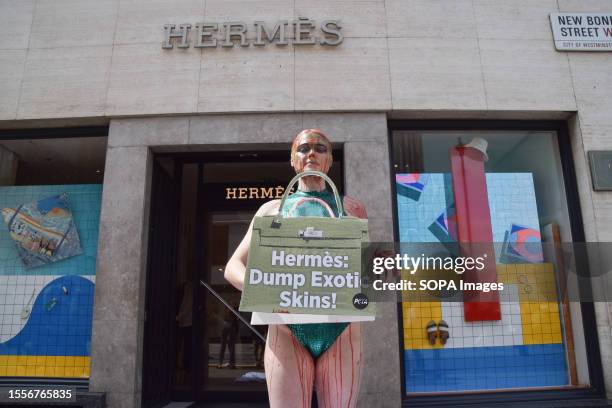 Vegan activist Tash Peterson, covered in fake blood, holds a mock Hermes bag and fake guts during the protest. PETA staged a protest outside the...