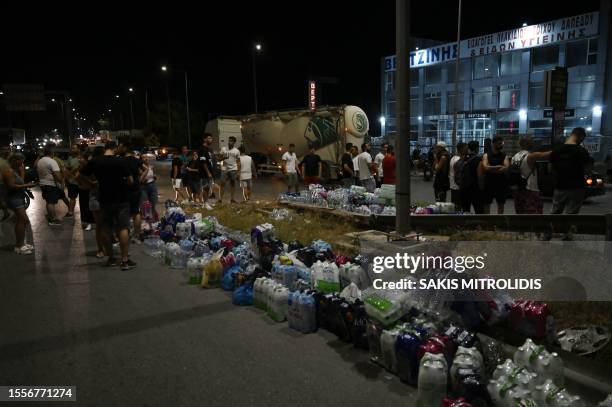 People bring bottles of water for firefighters during a wildfire near the city of Volos, central Greece, on July 26, 2023. New blazes threatened...