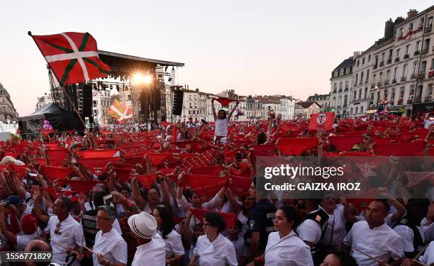 Revellers wave red bandanas as people gather in front of the town hall during the opening ceremony of the Bayonne festival , in Bayonne, soutwestern...