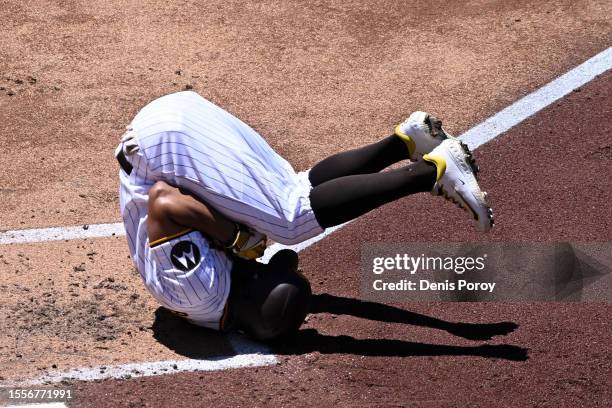 Xander Bogaerts of the San Diego Padres rolls after being hit with a pitch during the third inning of a baseball game against the Pittsburgh Pirates...