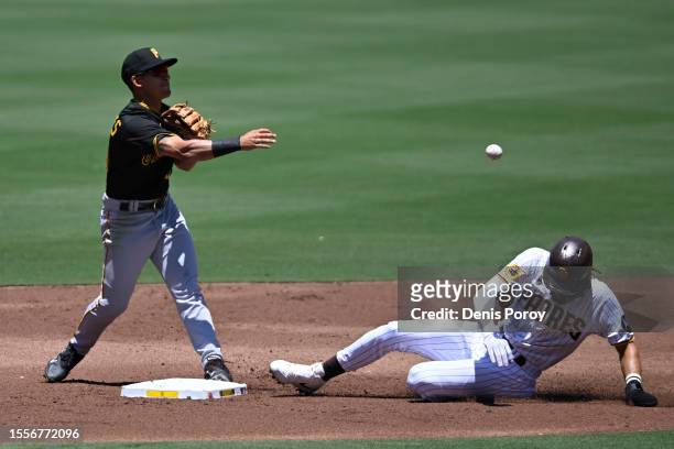 Nick Gonzales of the Pittsburgh Pirates throws over Fernando Tatis Jr. #23 of the San Diego Padres as he turns a double play during the second inning...