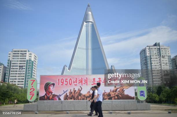 Pedestrians walk past the Ryugyong Hotel in Pyongyang on July 27 on the 70th anniversary of the end of the Korean War, which the country celebrates...