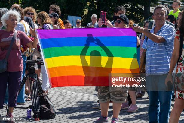 Couple carries a rainbow flag symbol of the lgtbi collective in the ''Kissing Meetup'' in the town hall square of the Cantabrian town of Bezana as a...