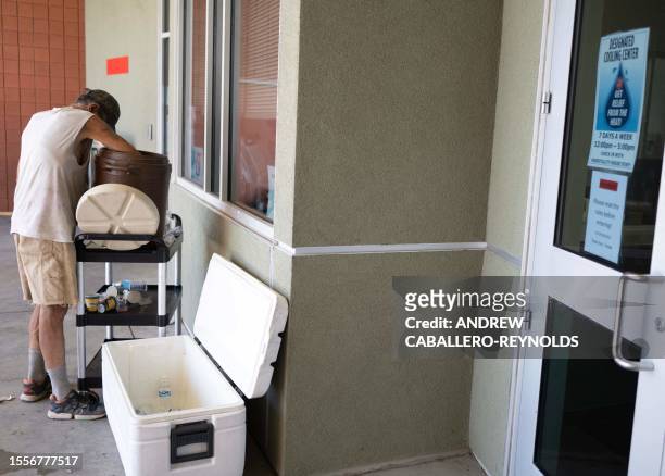 Man looks for ice in a water bucket at a Salvation Army cooling center for the homeless in Tucson, Arizona on July 26, 2023. A record-breaking heat...