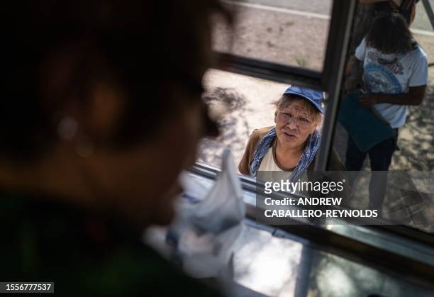Woman waits for water at a Salvation Army truck handing out water, and other supplies for the homeless in Tucson, Arizona on July 26, 2023. A...