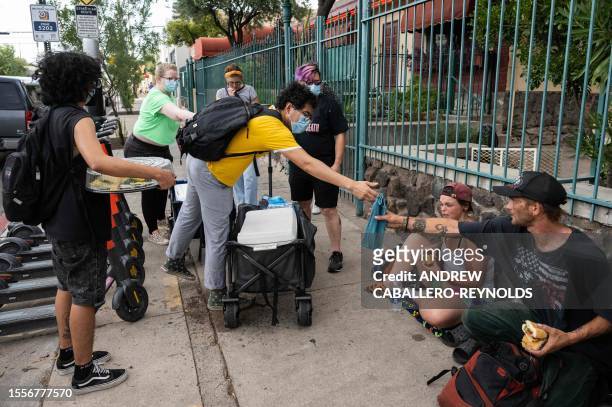Xavier Doblado with the mutual air group Gator-Aid hands out a wet cool towel to a family resting on the street in Tucson, Arizona on July 26, 2023....