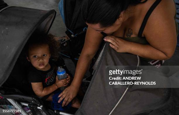 Brianna wipes her son with a wet cloth, given from volunteers with mutual air group Gator-Aid, as she waits with her family at a bus station to get...