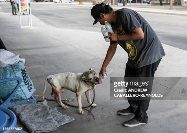 Rubin Munguies gives his dog Petey water donated by Gator-Aid volunteers at a bus station in Tucson, Arizona on July 26, 2023. The group walks...