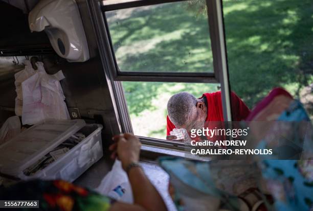 Joseph Guillory rubs his head with ice given to him at a Salvation Army truck handing out water, and other supplies for the homeless in Tucson,...