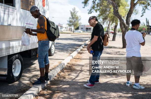 People wait in line for water at a Salvation Army truck handing out water, and other supplies for the homeless in Tucson, Arizona on July 26, 2023. A...
