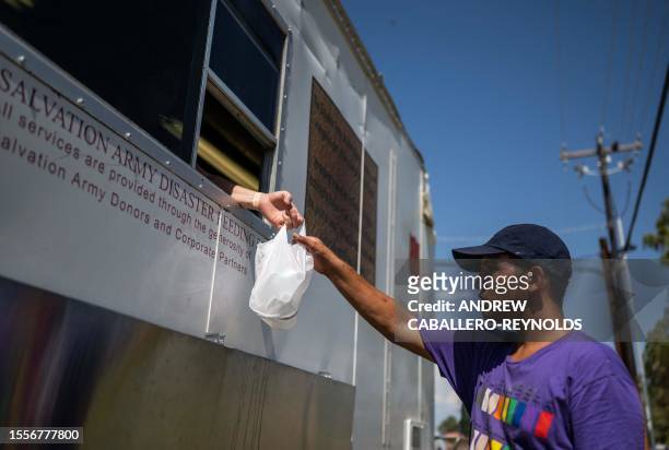 Man gets a bag of water and supplies at a Salvation Army truck handing out water, and other supplies for the vulnerable in Tucson, Arizona on July...