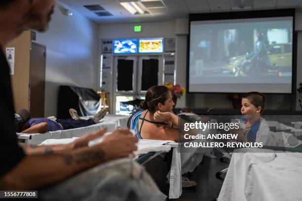 Nathaniel takes a drink as his mother Jennifer, and father Shaun look on as they rest on cots at a Salvation Army cooling center for the homeless in...