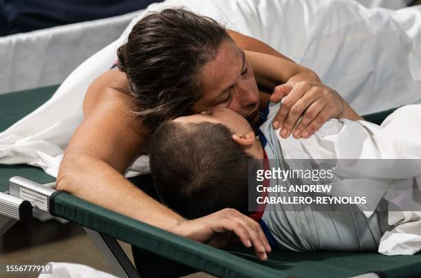 Nathaniel kisses his mother Jennifer, as they rest on a cot at a Salvation Army cooling center for the homeless in Tucson, Arizona on July 26, 2023....