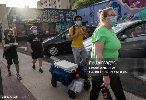 Kristin Brooks pulls a cart with water and other supplies near other volunteers with mutual air group Gator-Aid in Tucson, Arizona on July 26, 2023....