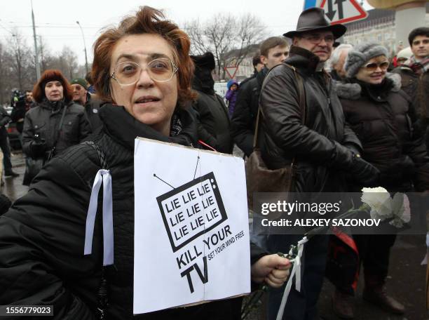 An opposition supporter carries a poster during a rally in front of the television broadcasting center in Moscow on March 18, 2012. Riot police...