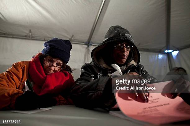 Poll workers Diane DeStefano and Ernestine Dickerson bundle up against the cold while assisting voters in the presidential elections in a tent in the...