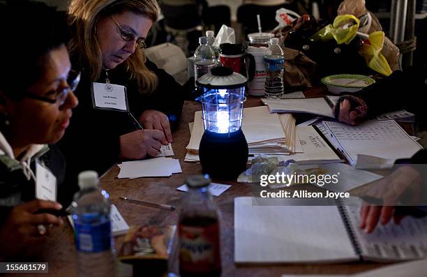 Poll workers work by generator lights and a small battery run portable light in the presidential elections in a tent in Midland Beach November 6,...