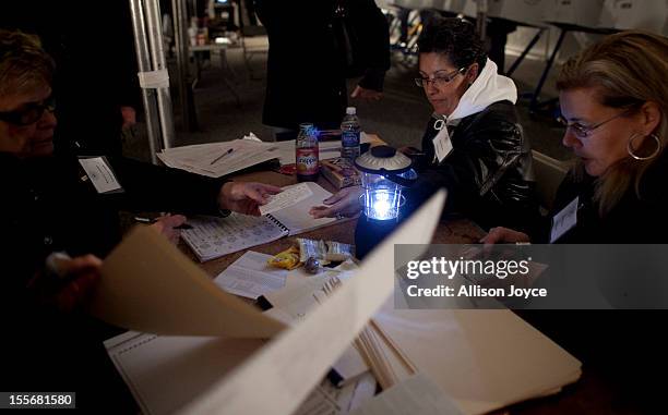 Poll workers work by generator lights and a small battery run portable light in the presidential elections in a tent in Midland Beach November 6,...