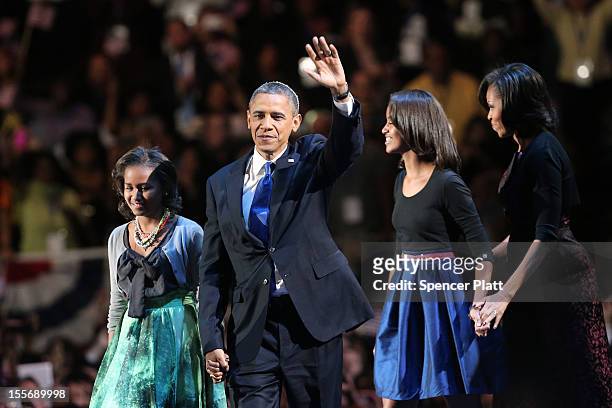 President Barack Obama walks on stage with first lady Michelle Obama and daughters Sasha and Malia to deliver his victory speech on election night at...
