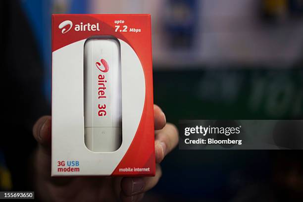Shopkeeper holds a Bharti Airtel Ltd. 3G USB modem for a photograph in a mobile services store in New Delhi, India, on Tuesday, Nov. 6, 2012. Bharti...