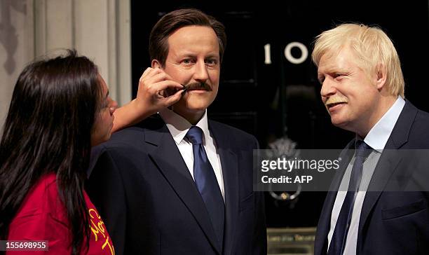 Make-up technician adjusts the moustaches on the wax figure of British Prime Minister David Cameron and Mayor of London Boris Johnson at Madame...