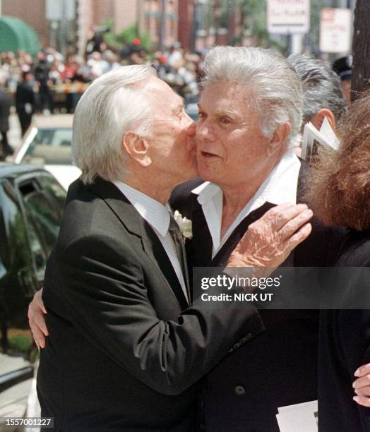 Actors Kirk Douglas, , and Tony Curtis, , hug following the funeral of entertainer Frank Sinatra at the Good Sheperd Catholic Church in Beverly Hills...