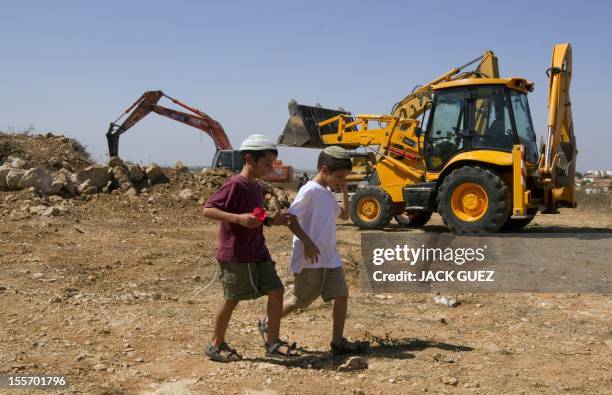 Children of Israeli settlers walk past tractors on September 27, 2010 at the construction site for 50 housing units in the West Bank settlement of...