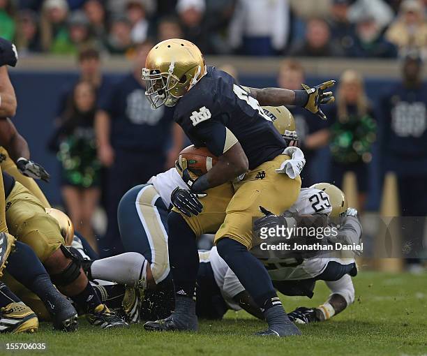Theo Riddick of the Notre Dame Fighting Irish is dropped for a loss by Aaron Donald, Joe Trebitz and Jason Hendricks of the Pittsburgh Panthers at...