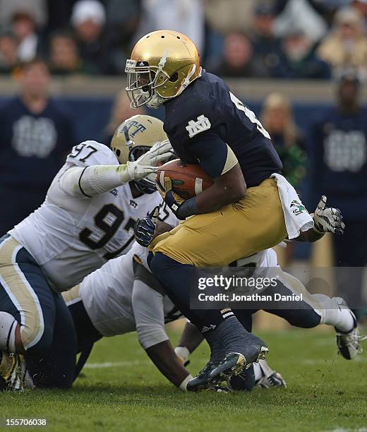 Theo Riddick of the Notre Dame Fighting Irish is dropped for a loss by Aaron Donald, Joe Trebitz and Jason Hendricks of the Pittsburgh Panthers at...