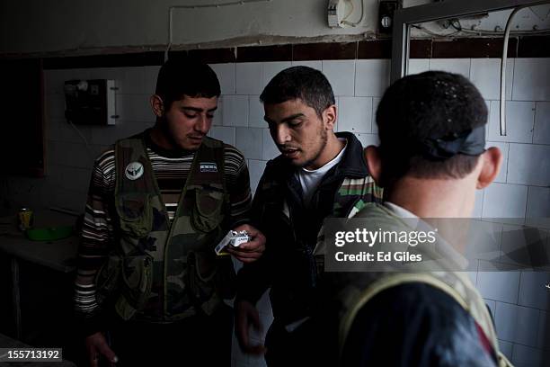 Fighters from the Shohada al Haq brigade of the Free Syrian Army share cigarettes during a raid to clear a new apartment building in the no-mans land...