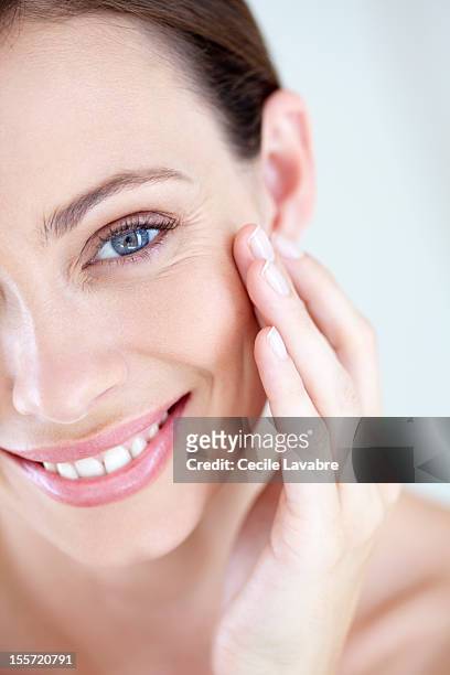 a smiling woman touching her face - wrinkles fotografías e imágenes de stock