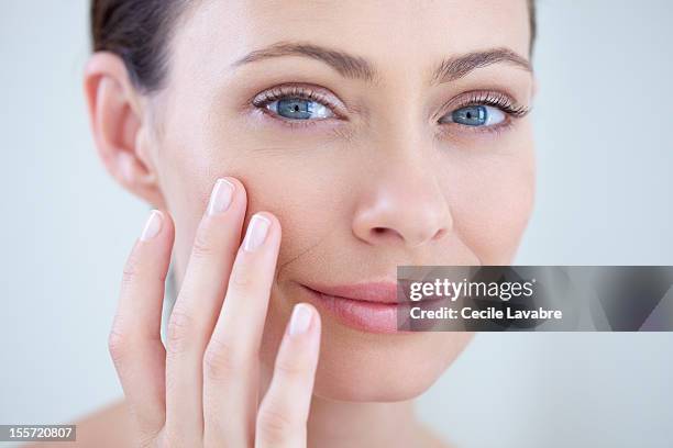 woman examining her face with her fingers - wrinkles fotografías e imágenes de stock