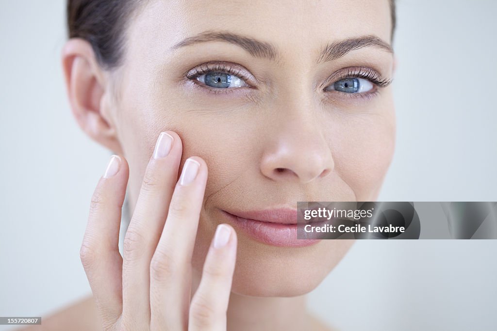 Woman examining her face with her fingers