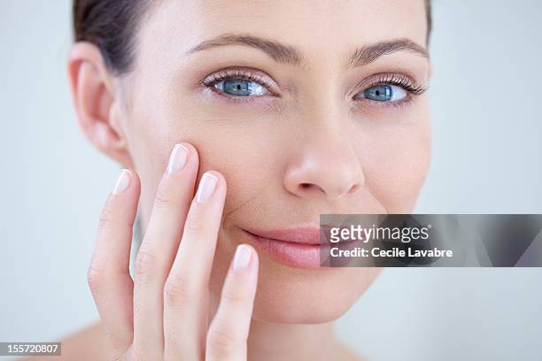 woman examining her face with her fingers - cheek - fotografias e filmes do acervo