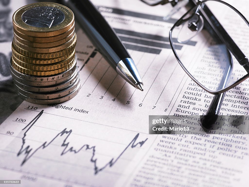 A financial chart with coins, glasses and pen