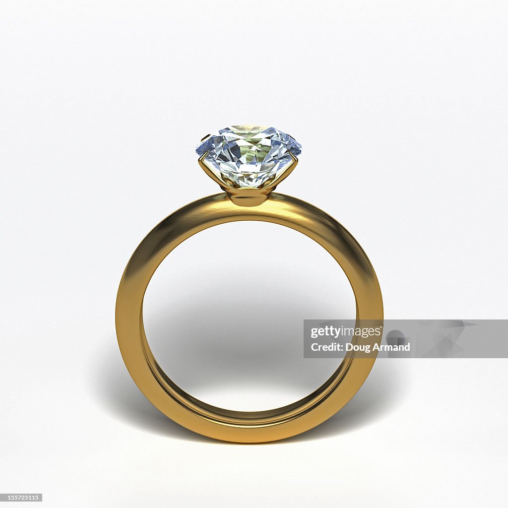 Gold diamond ring upright on white surface