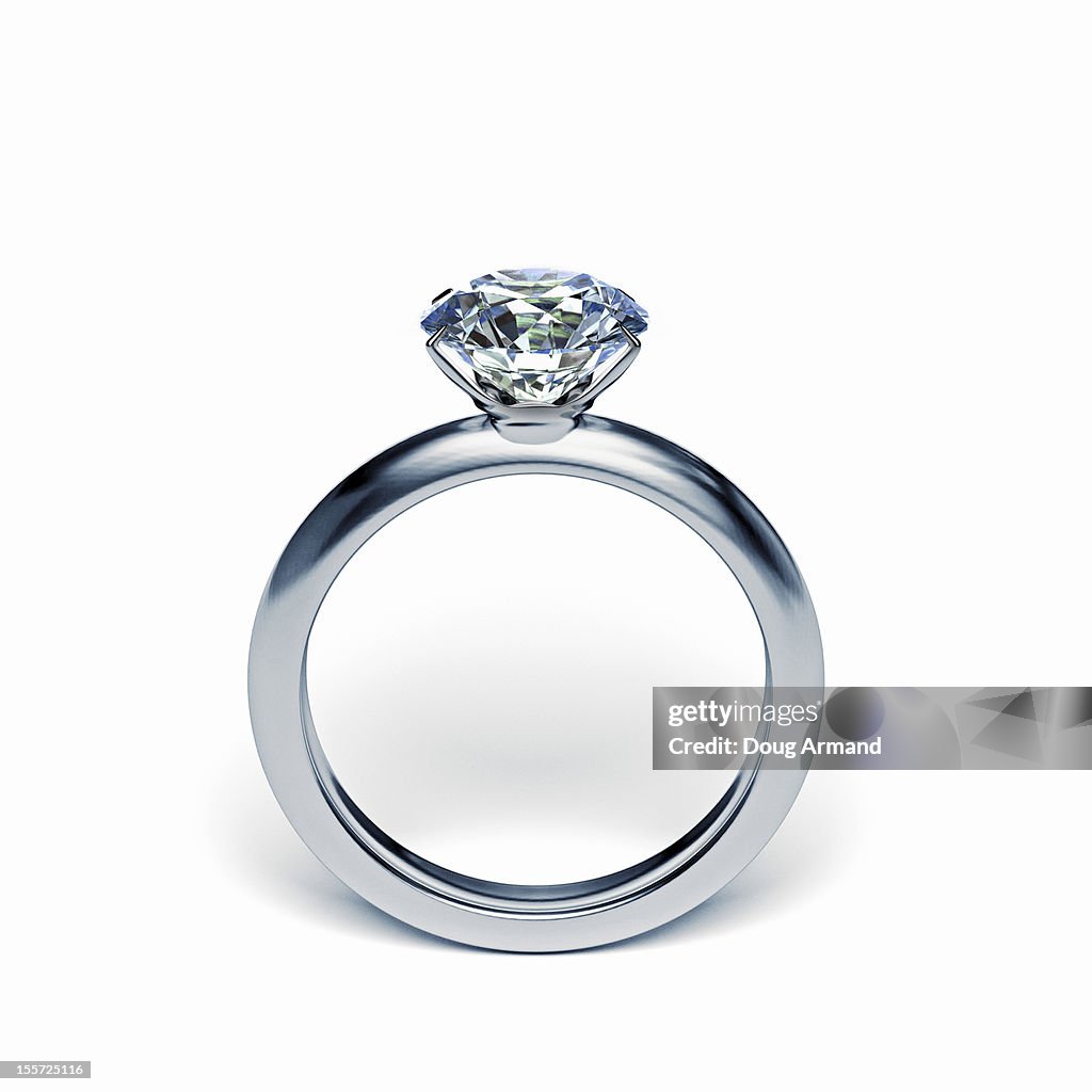 Silver diamond ring upright on white surface