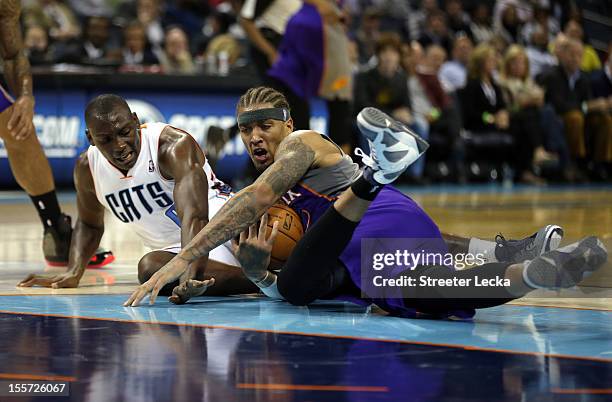 Bismack Biyombo of the Charlotte Bobcats and Michael Beasley of the Phoenix Suns battle for a loose ball during their game at Time Warner Cable Arena...