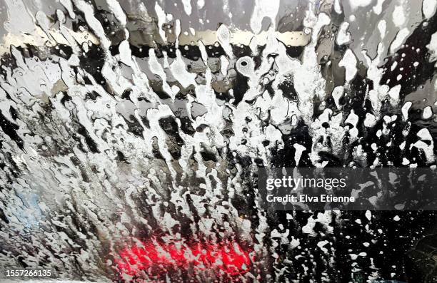 view from the inside out, through a wet windscreen covered in soap suds in the process of being cleaned during an automatic tunnel car wash. - drive through car wash stock pictures, royalty-free photos & images