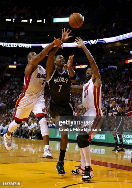 Joe Johnson of the Brooklyn Nets drives against Dwyane Wade and Udonis Haslem of the Miami Heat during a game at AmericanAirlines Arena on November...