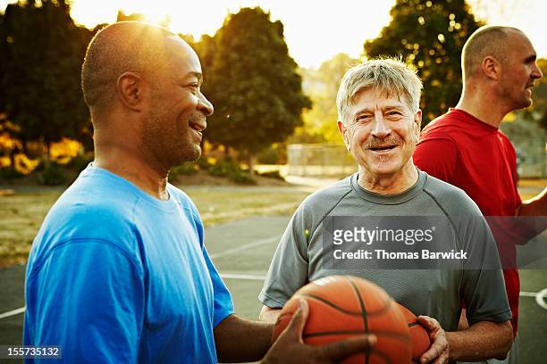 group of basketball players on outdoor court - conversation sunset stock-fotos und bilder